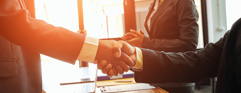 Two people shaking hands in a business setting.